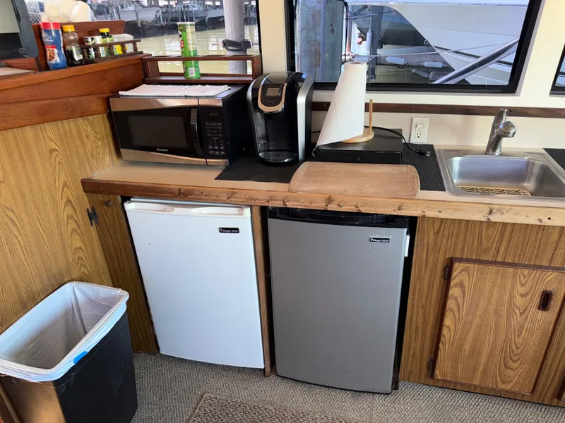 Slide: The Image of 1981 Bertram 38 Convertible kitchen with microwave, mini-fridges, sink, and countertop appliances. - 16
