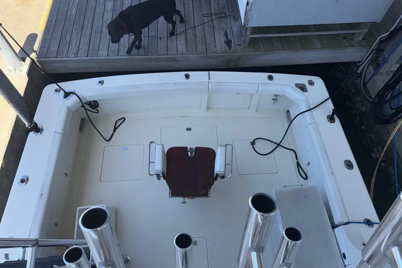 Slide: The Image of 1981 Bertram 38 Convertible boat deck with fishing rod holders, docked near a wooden pier. - 22