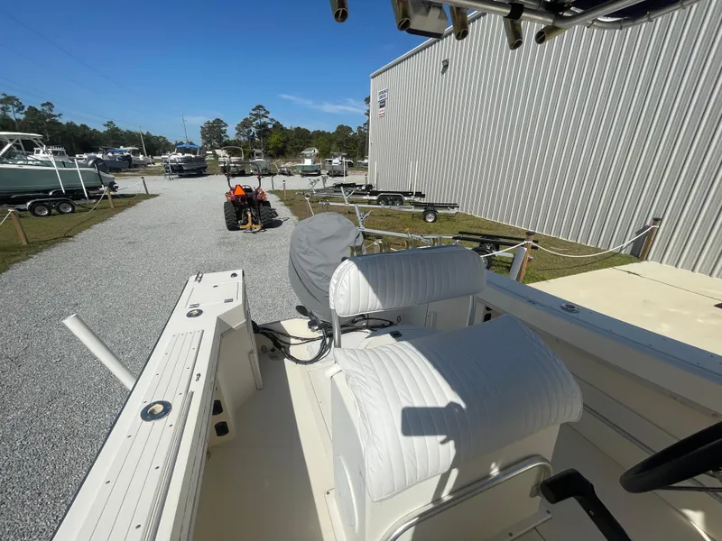 Slide: The Image of KenCraft Challenger 215 boat interior with white seating, parked near trailers and a building. - 21