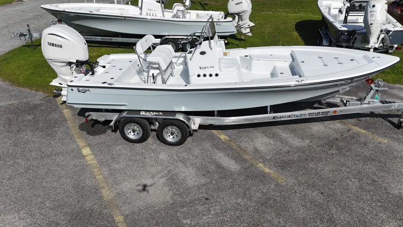 Slide: The Image of 2025 BlackJack 224 boat on trailer, parked in a lot with other boats. - 20