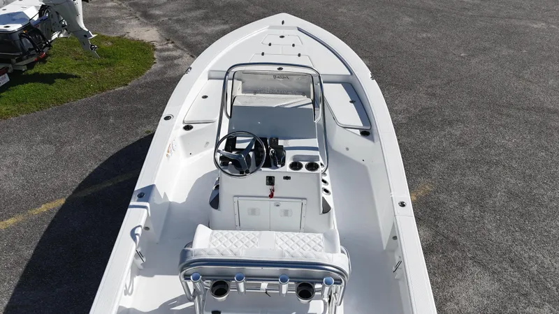 Slide: The Image of 2025 BlackJack 224 boat, white interior, center console, steering wheel, and seating, parked on asphalt. - 9