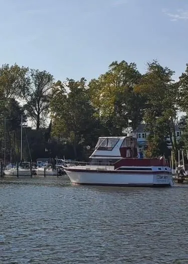 Slide: The Image of 1985 Wellcraft California boat docked on a calm river, surrounded by trees and other boats. - 3