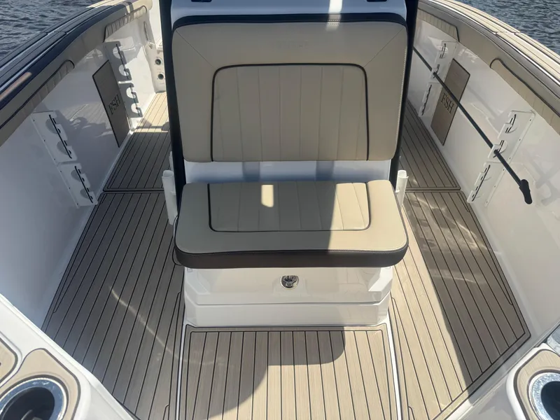 Slide: The Image of 2023 Yamaha Boats 255 FSH Sport E interior with beige seating and sleek deck design. - 12
