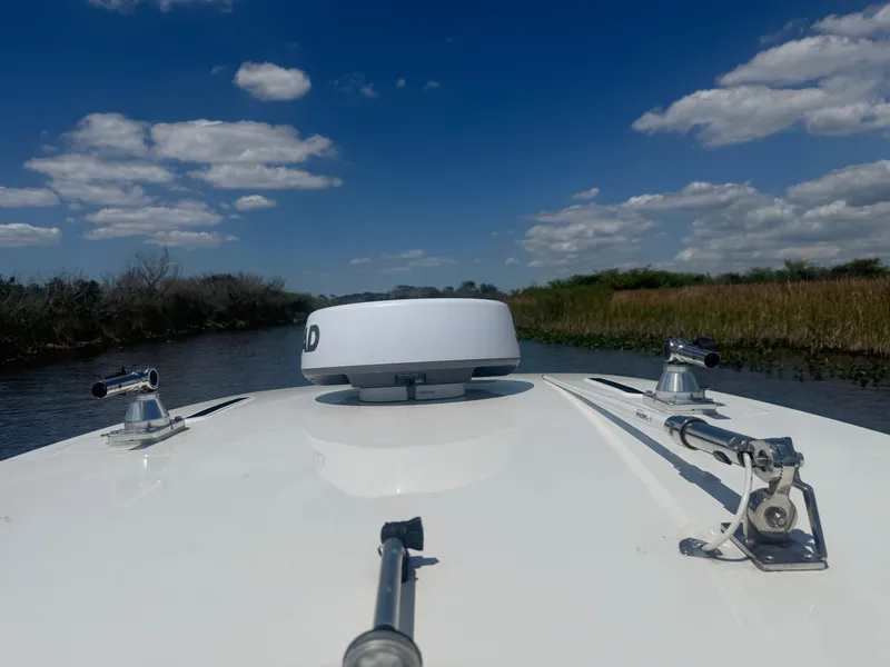 Slide: The Image of 2023 Yamaha Boats 255 FSH Sport E navigating a serene waterway under a blue sky. - 16