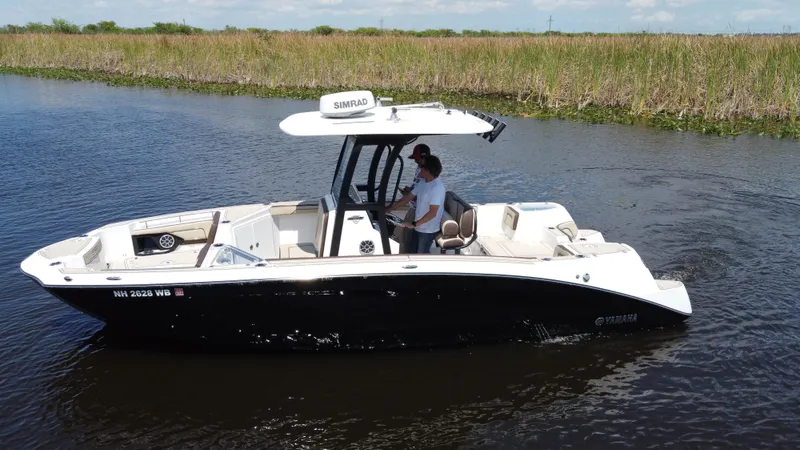 Slide: The Image of 2023 Yamaha Boats 255 FSH Sport E cruising on a calm river. - 5