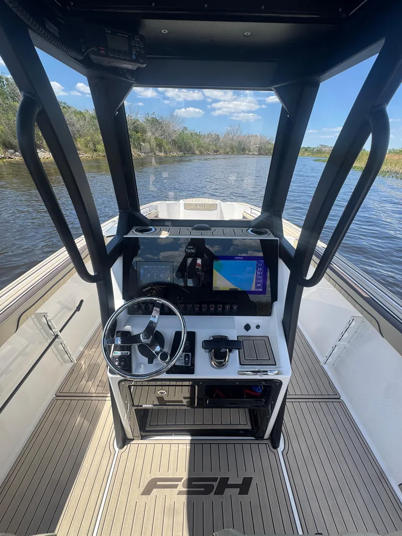 Slide: The Image of 2023 Yamaha Boats 255 FSH Sport E dashboard with navigation system on a calm river. - 7