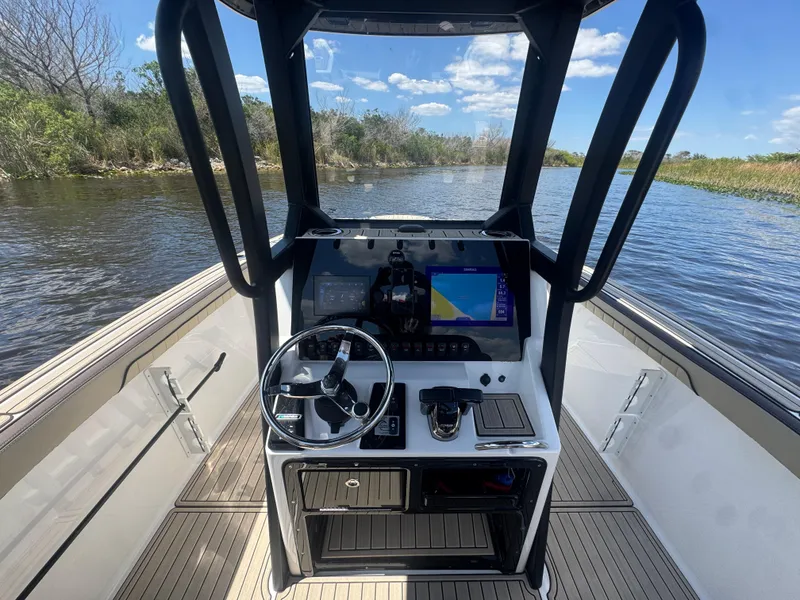 Slide: The Image of 2023 Yamaha Boats 255 FSH Sport E dashboard with steering wheel and navigation screen on water. - 8