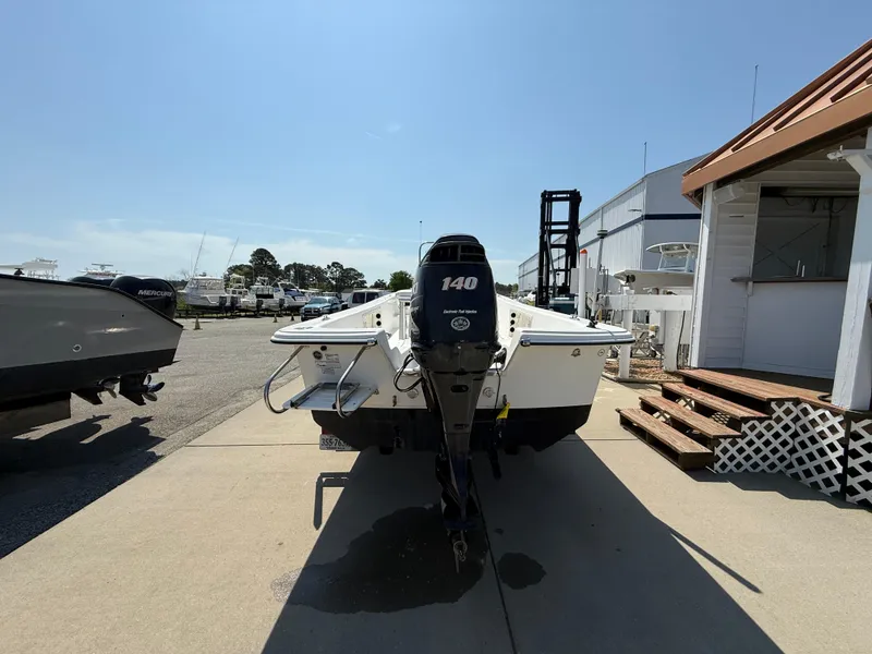 Slide: The Image of 2010 Carolina Skiff 218 ELV boat with 140 HP engine, parked outdoors. - 3