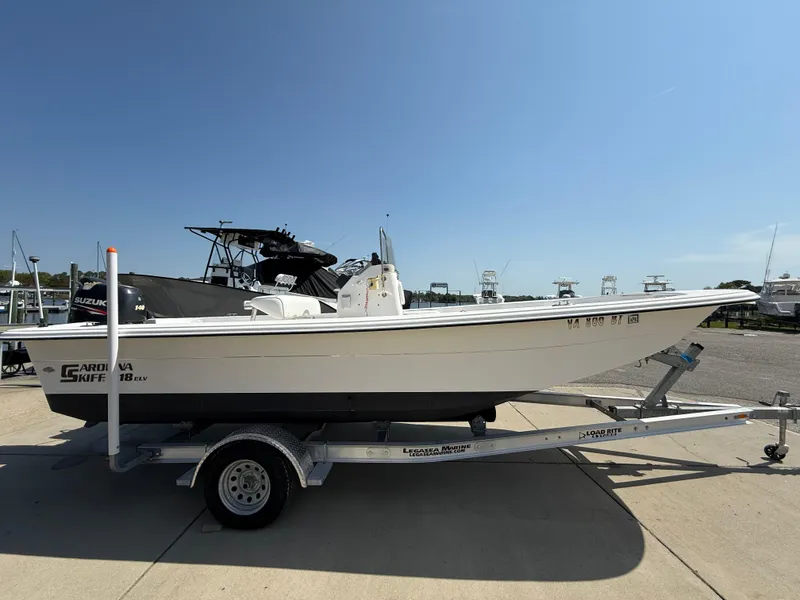 Slide: The Image of 2010 Carolina Skiff 218 ELV boat on trailer, parked outdoors under clear sky. - 5