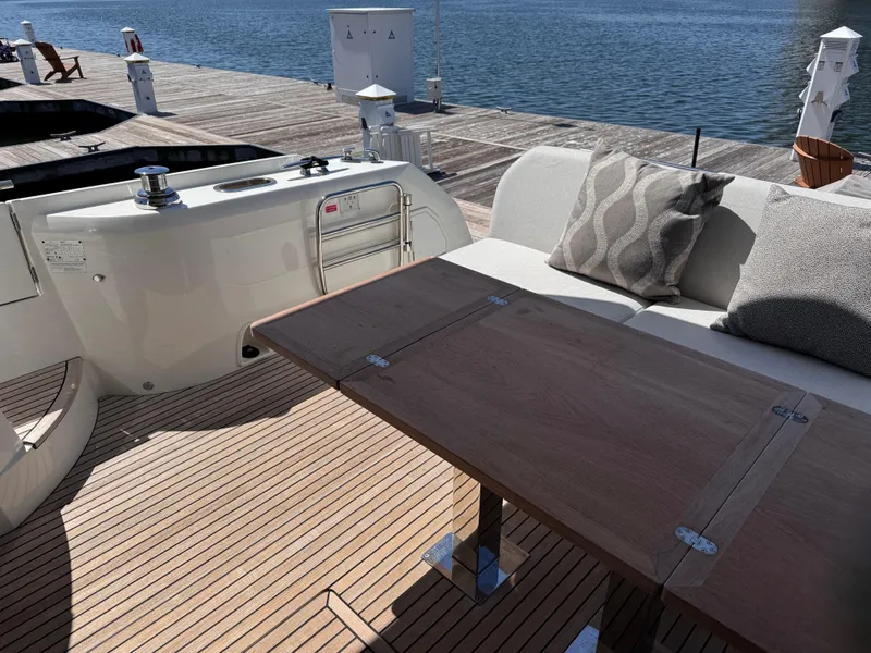 Slide: The Image of 2023 Prestige 520 F-Line yacht deck with wooden table and cushioned seating by the water. - 44