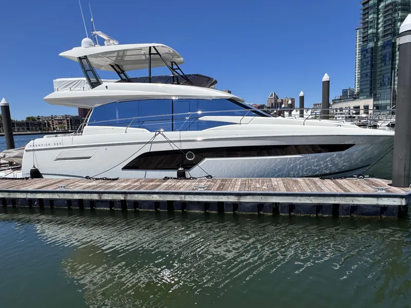 Slide: The Image of 2023 Prestige 520 F-Line yacht docked at marina, clear blue sky, modern waterfront buildings. - 6