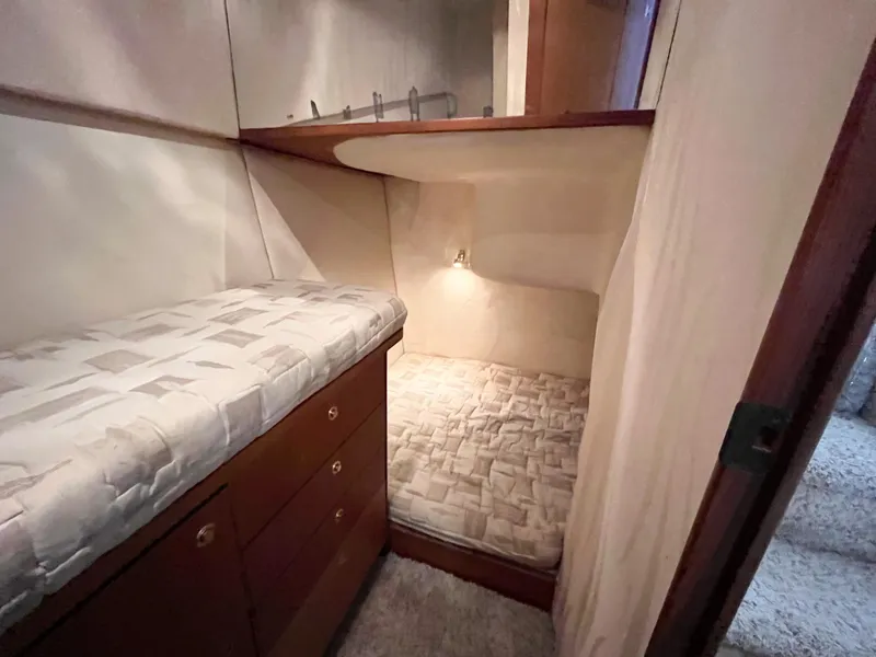 Slide: The Image of 2002 Ocean Yachts 48 Super Sport cabin interior with cozy bedding and wooden storage. - 13
