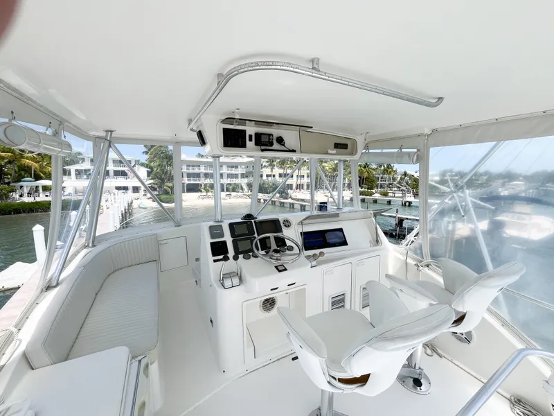 Slide: The Image of 2002 Ocean Yachts 48 Super Sport helm with modern controls and seating, docked near waterfront homes. - 26