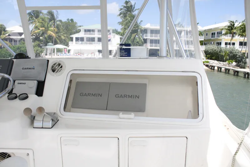 Slide: The Image of 2002 Ocean Yachts 48 Super Sport helm with Garmin navigation equipment, docked near waterfront homes. - 30