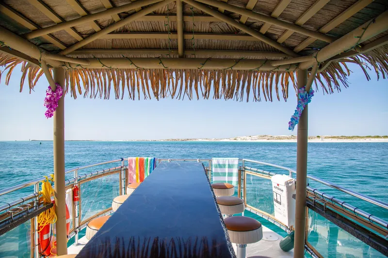 Slide: The Image of Tiki boat with bar seating, ocean view, colorful towels, and thatched roof. - 15