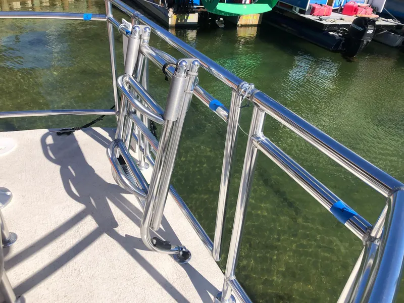 Slide: The Image of 2022 Beachcat COI Tiki Boat with stainless steel railing on calm water. - 16