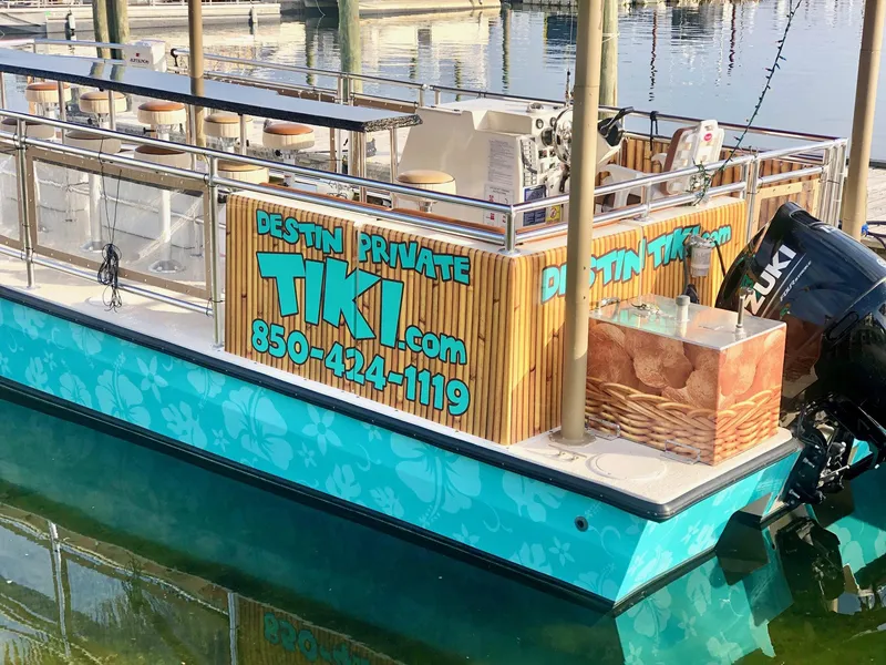 Slide: The Image of 2022 Beachcat COI Tiki Boat docked, featuring vibrant tropical design and contact details for private charters. - 5