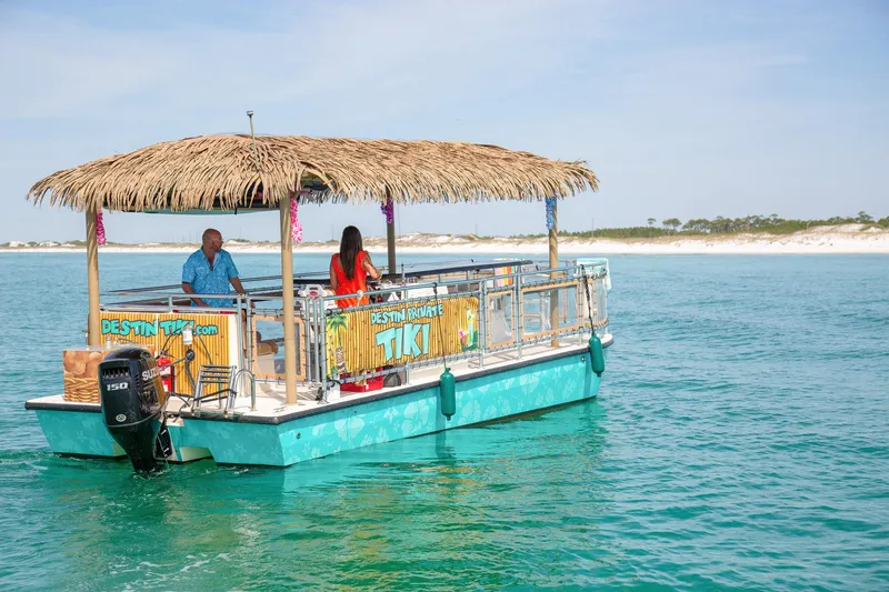 Slide: The Image of 2022 Beachcat COI Tiki Boat on turquoise water with thatched roof and passengers. - 7
