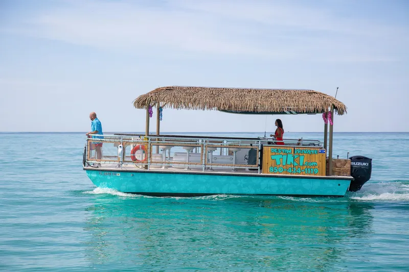 Slide: The Image of 2022 Beachcat COI Tiki Boat cruising on clear blue water with thatched roof. - 8