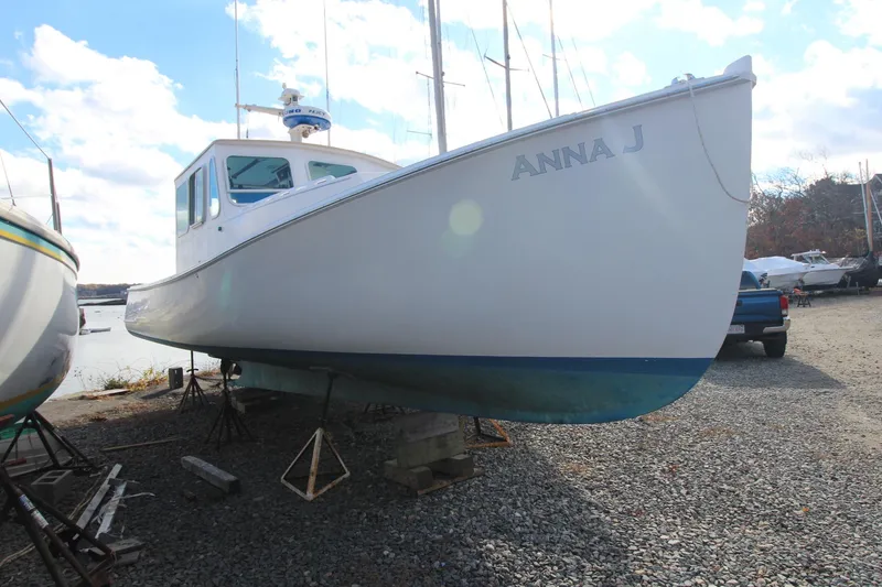 Slide: The Image of 2020 Holland 32 boat named "Anna J" on dry dock, gravel ground, clear sky. - 4