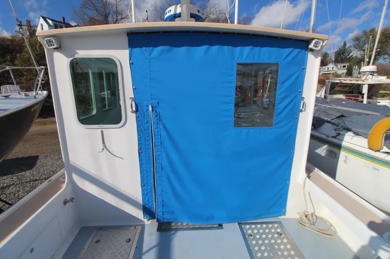 Slide: The Image of Holland 32 boat, 2020 model, with blue canvas door cover and window, docked outdoors. - 9
