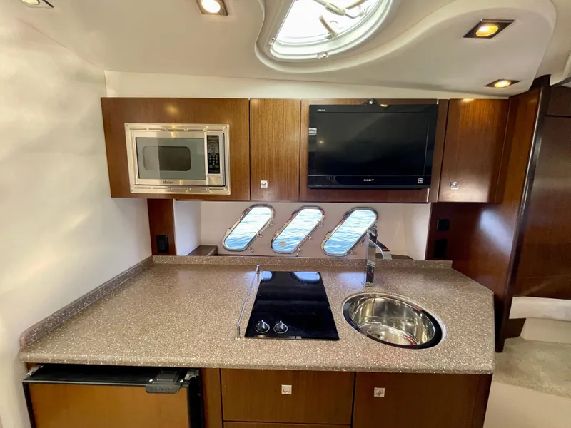 Slide: The Image of 2012 Cruisers Yachts 35 Express kitchen with microwave, stove, sink, and TV. - 16