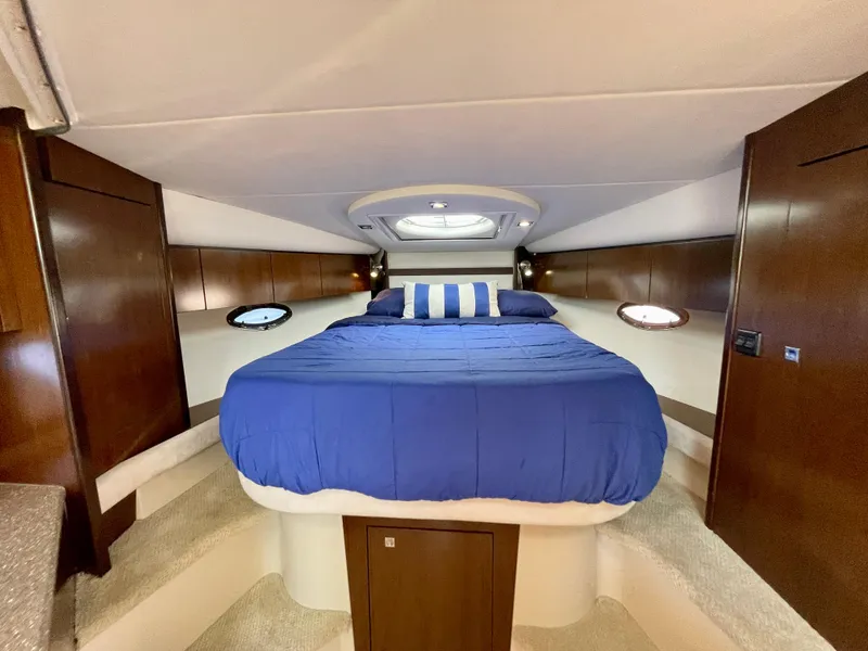 Slide: The Image of 2012 Cruisers Yachts 35 Express cabin with blue bedding and wooden interior. - 19