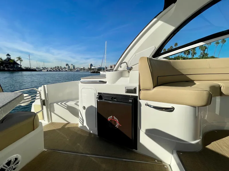 Slide: The Image of 2012 Cruisers Yachts 35 Express interior with seating, fridge, and scenic waterfront view. - 35