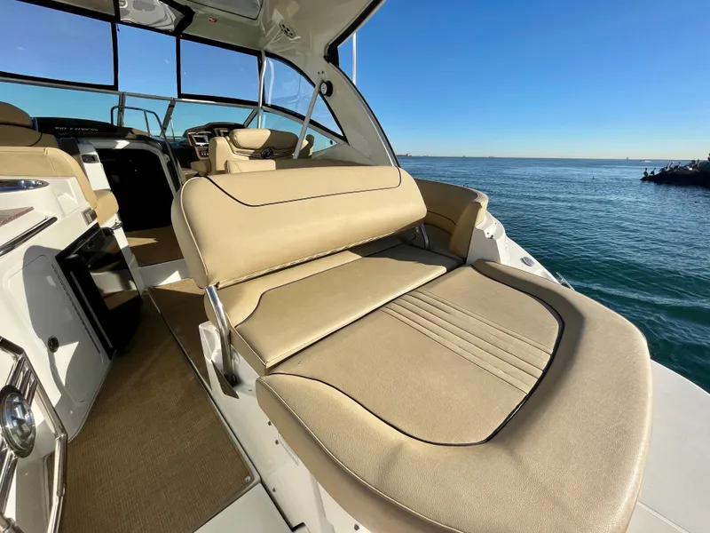 Slide: The Image of 2012 Cruisers Yachts 35 Express interior with beige seating, overlooking calm ocean waters. - 37