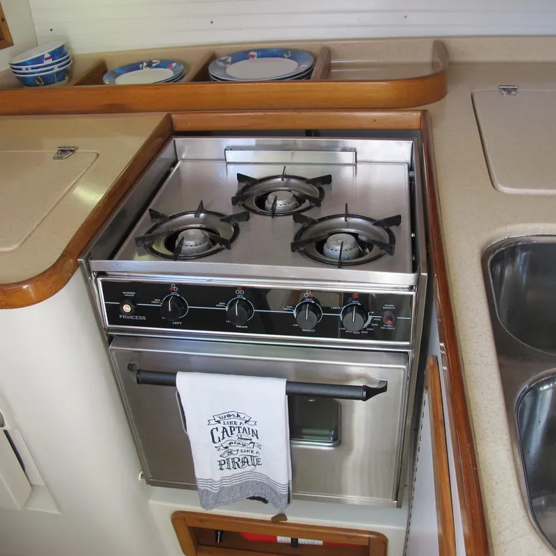 Slide: The Image of 2007 Catalina 387 yacht kitchen with stainless steel stove and oven, featuring nautical-themed towel. - 36