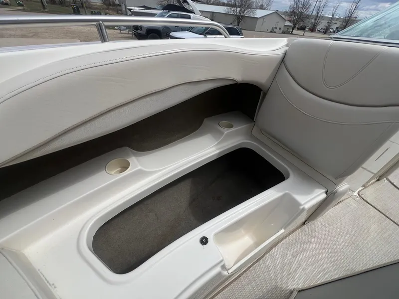 Slide: The Image of 2002 Maxum 2300 SR boat interior storage compartment with cup holders, featuring white upholstery. - 13