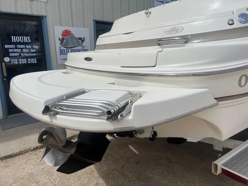 Slide: The Image of 2002 Maxum 2300 SR boat stern with swim platform and ladder, parked near a building. - 9