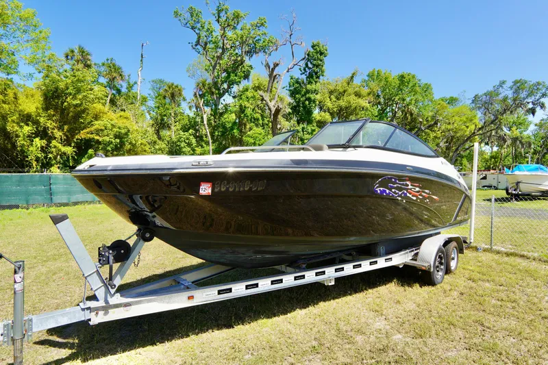 The Image of 2015 Yamaha Boats 242 Limited S on trailer, parked outdoors with lush greenery background. - 0