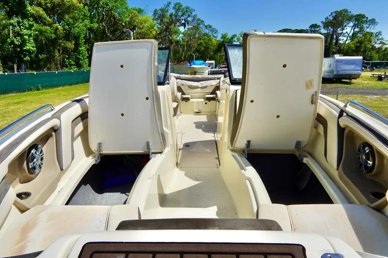 Slide: The Image of 2015 Yamaha Boats 242 Limited S interior with open storage compartments, surrounded by lush greenery. - 13