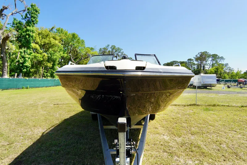 Slide: The Image of 2015 Yamaha Boats 242 Limited S on trailer, parked on grassy area with trees in background. - 2