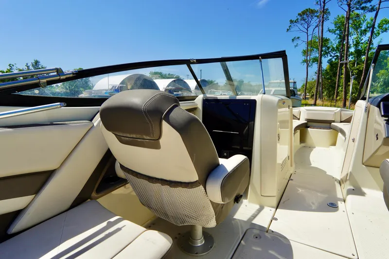 Slide: The Image of 2015 Yamaha Boats 242 Limited S interior with seating and dashboard, under clear blue sky. - 26