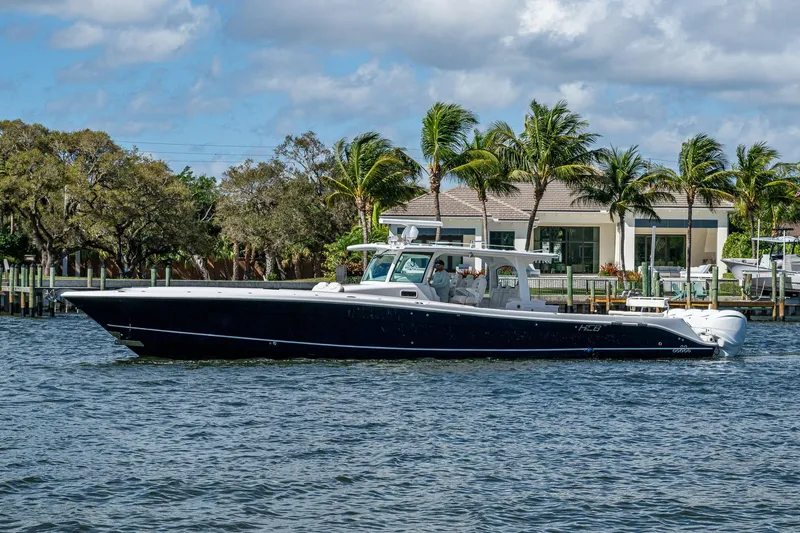 Slide: The Image of 2020 HCB 53 boat cruising on a sunny day near waterfront homes. - 0