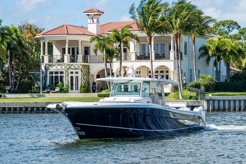 Slide: The Image of 2020 HCB 53 boat cruising near a luxurious waterfront mansion with palm trees. - 1