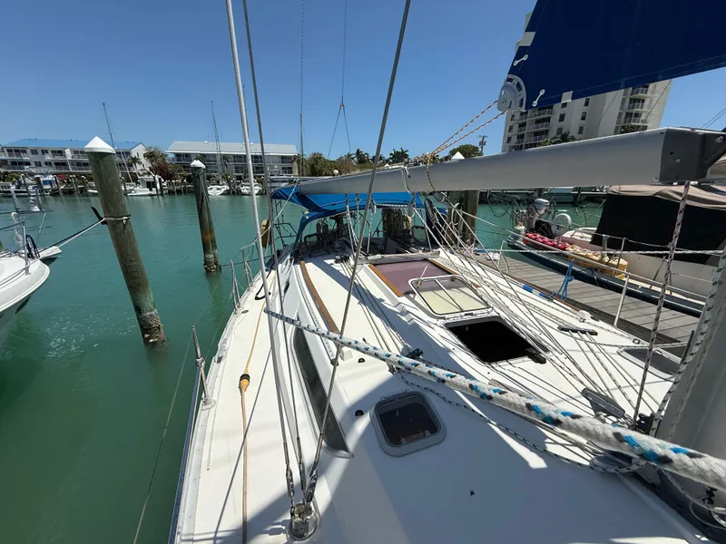 Slide: The Image of Sailboat Jeanneau Sun Odyssey 42.2, 1998 model, docked in a marina with clear blue water. - 23