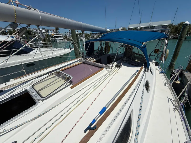 Slide: The Image of 1998 Jeanneau Sun Odyssey 42.2 sailboat docked, featuring a blue canopy and clean deck. - 27