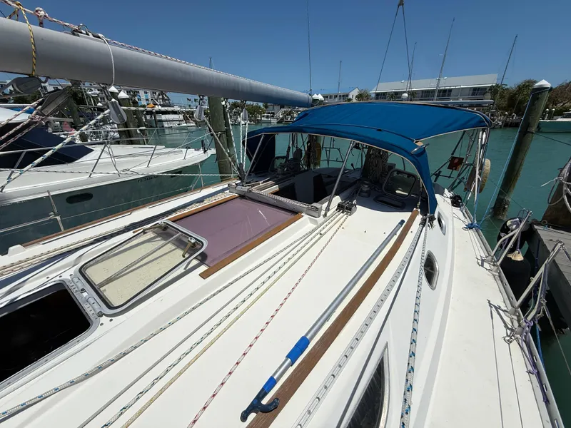 Slide: The Image of 1998 Jeanneau Sun Odyssey 42.2 sailboat docked, featuring a blue canopy and clean deck. - 28