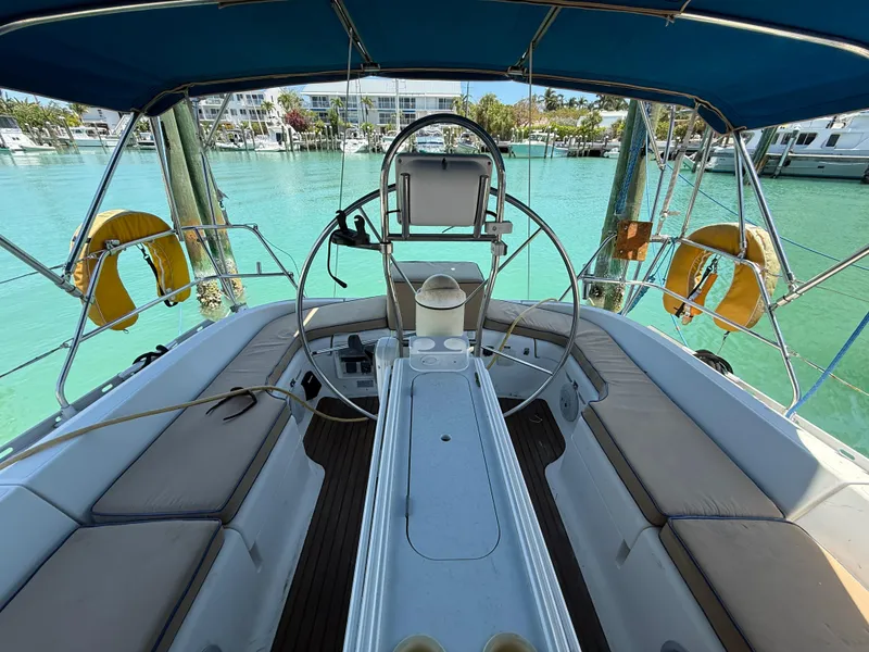 Slide: The Image of Cockpit view of 1998 Jeanneau Sun Odyssey 42.2 sailboat with blue canopy and marina backdrop. - 32