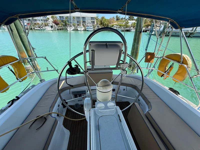 Slide: The Image of Cockpit of 1998 Jeanneau Sun Odyssey 42.2 sailboat with blue canopy and scenic marina view. - 42