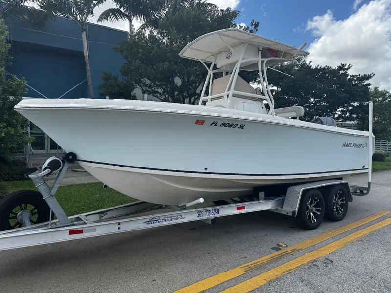 Slide: The Image of 2015 Sailfish 220 CC boat on trailer, parked on roadside under cloudy sky. - 0