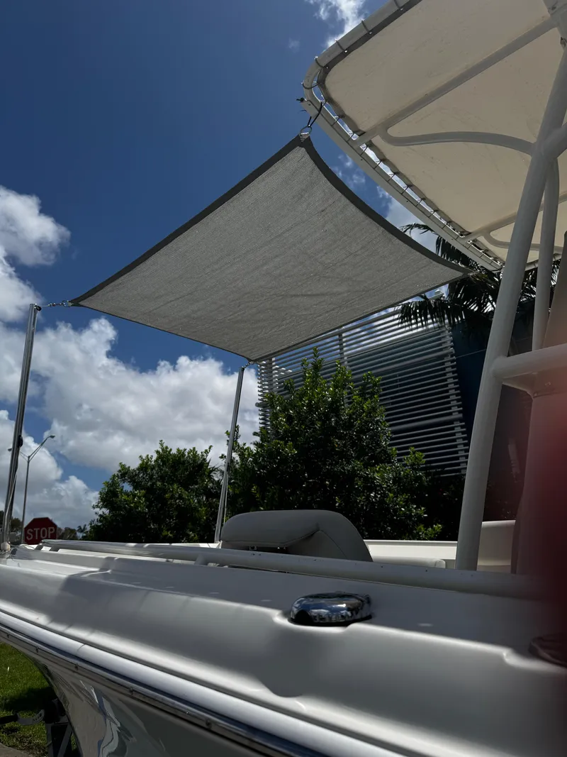 Slide: The Image of 2015 Sailfish 220 CC boat with sunshade, under a clear blue sky. - 3
