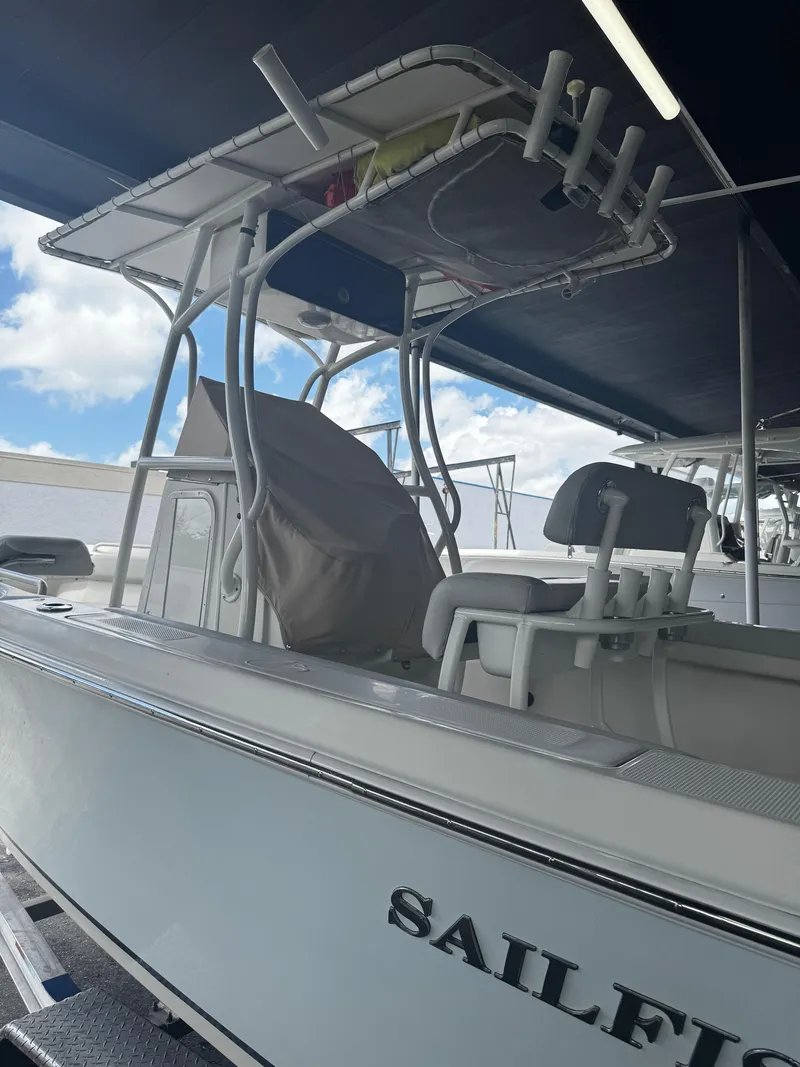 Slide: The Image of 2015 Sailfish 220 CC boat with T-top and seating, docked under shelter. - 5
