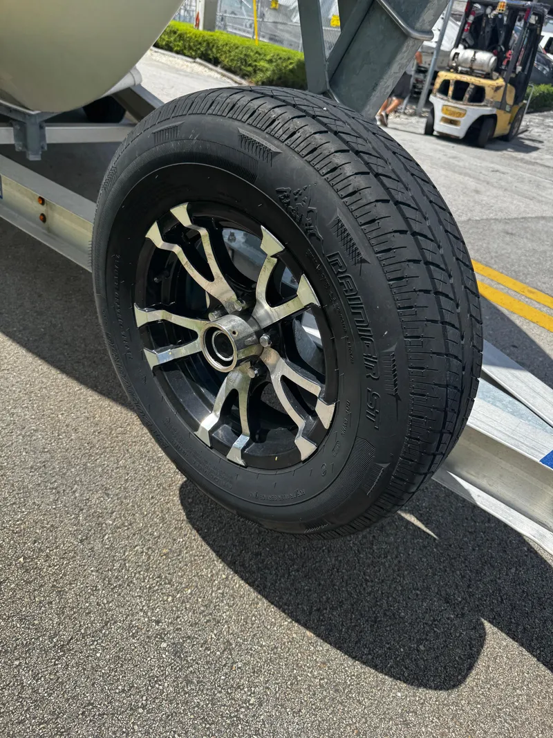 Slide: The Image of Trailer wheel of a 2015 Sailfish 220 CC boat on pavement. - 8