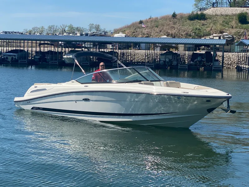Slide: The Image of 2012 Sea Ray 270 SLX boat cruising on a calm lake near a marina. - 0