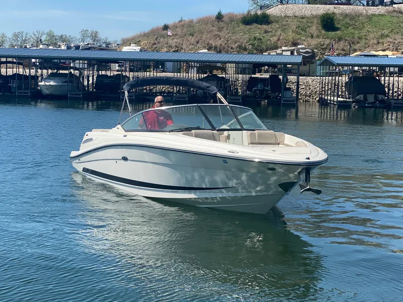 Slide: The Image of 2012 Sea Ray 270 SLX boat cruising on a calm lake near a marina. - 1