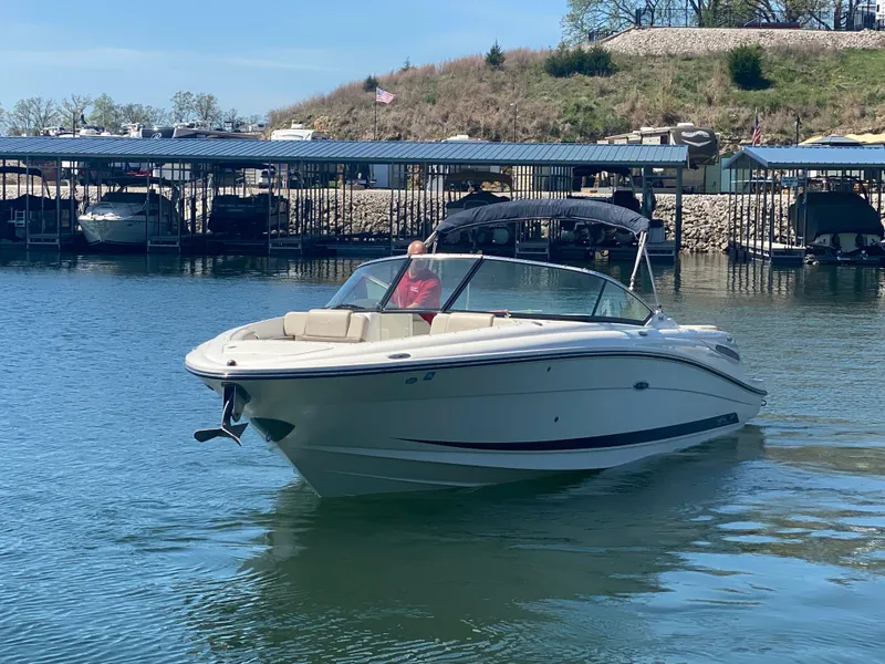 Slide: The Image of 2012 Sea Ray 270 SLX boat cruising on a calm lake near a marina. - 2